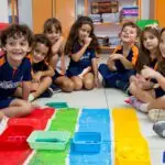 Alunos do 2º Período da Educação Infantil, com idade entre 5 e 6 anos, tingindo palitos de picolé nas cores vermelha, verde, azul e amarela.