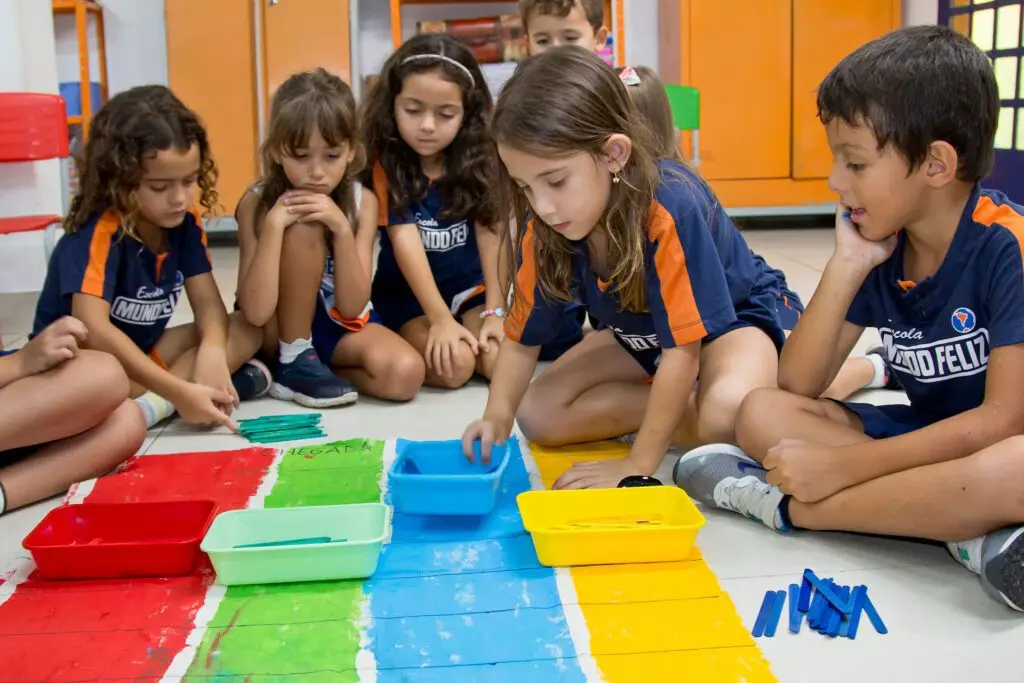 Alunos do 2º Período da Educação Infantil, com idade entre 5 e 6 anos, pintando faixas, vermelha, verde, azul e amarela.