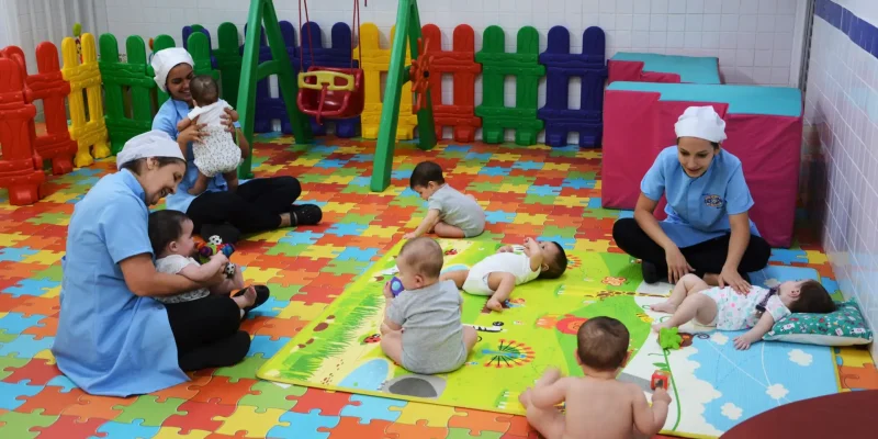 Berçário Diversos bebês relaxando e se divertindo em uma área multicolorida do Berçário, sempre assistidos e entretidos pelas berçaristas da Escola Mundo Feliz.